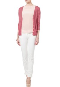 Let cardigan af strik med knapper i rosenrød, kombineret med en blød lyserød bluse; stramme hvide jeans og nøgne hæle fuldender outfittet.