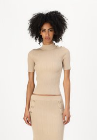 Beige ribbede kortermet topp med høy hals, med dekorative knapper på skulderen og en tettsittende silhuett.