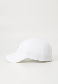 Căciulă de baseball albă cu un vizor curbat, curea de ajustare la spate și găuri de ventilație coase pe panourile superioare. Design simplu cu accente minime.