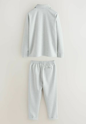Lysegrå langærmet polo med krave, kombineret med matchende joggingbukser med elastisk taljebånd og manchetter ved benene.