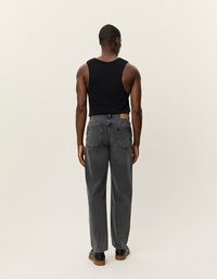 Pelēki džinsi ar brīvu piegriezumu un augstu jostasvietu, apvienoti ar melnu bezdelgīti. Raksturīgas ādas taga un aizmugurējās kabatas. Melna apave.