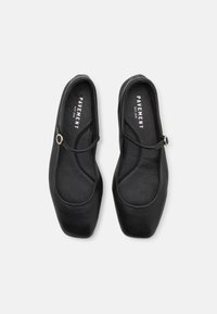 Black flat shoes with a square toe, made of smooth leather. Features a thin buckle strap and a padded insole for comfort. Brand logo inside.