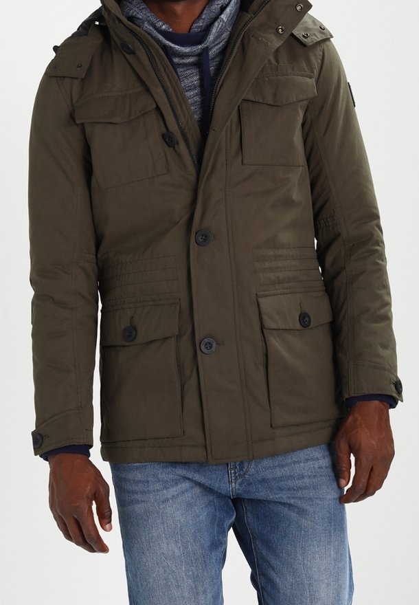 Parka matelassée vert olive avec fermeture éclair et boutons, deux grandes poches avant, et capuche amovible avec pressions.