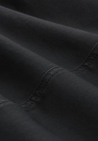 Tissu noir au toucher lisse, affichant un léger brillant. Des coutures visibles apportent une finition soignée.