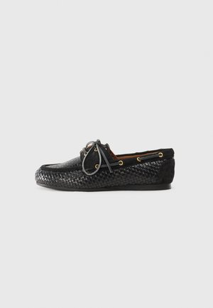 Black woven leather loafer with a smooth suede heel panel, round toe, decorative lacing, and gold-tone eyelets. Textured surface detail.