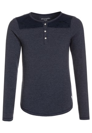 T-shirt enfant manches longues côtelé gris foncé avec trois boutons blancs et détail en dentelle sur le haut de la poitrine.