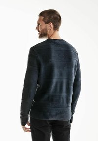 Pull en maille bleu marine avec des rayures horizontales texturées, des poignets et un ourlet côtelés, un col rond et une coupe décontractée. Fabriqué dans un matériau doux et chaud.