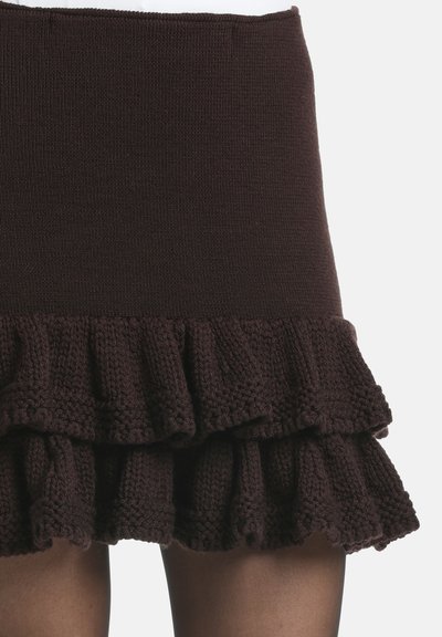 Jupe en tricot marron avec un haut ajusté et un bas à volants. La texture est côtelée avec un motif décoratif en couches au niveau de l'ourlet.