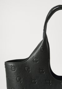 Sac à épaule en cuir noir avec un motif de logo gaufré, un dessus courbé, une seule sangle et une texture lisse. Design simple et moderne.