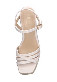 Sandalía blanca con tiras y tacón cuadrado, que presenta un material suave, hebilla ajustable y textura trenzada en la suela de cuña.