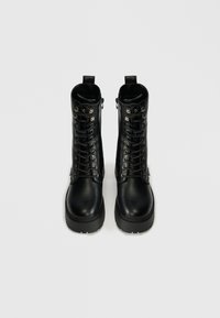 Μαύρες δερμάτινες μποτες αστραγάλου με κορδόνια, πλευρικούς φερμουάρ και χοντρές σόλες με υφή.