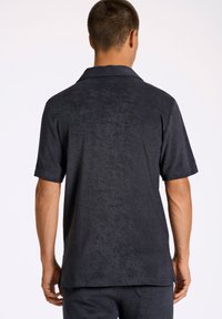 Camicia da uomo a maniche corte, grigia scura, realizzata in tessuto morbido con una finitura testurizzata. Caratterizzata da un colletto e un design relaxed fit.