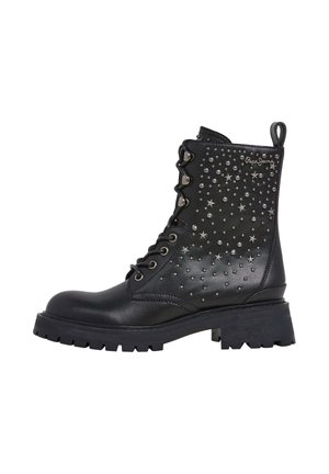 Botas de cuero negro hasta el tobillo con suela gruesa, adornadas con tachuelas plateadas y acentos en forma de estrella en el lado exterior, y diseño de cordones.