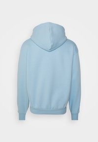Sudadera con capucha de color azul claro, fabricada en tejido suave, con un corte holgado, puños acanalados y un bolsillo tipo canguro. Se muestra la vista trasera.