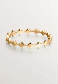 Pulsera de brazalete ondulado en tono dorado con un diseño en zigzag, bordes suaves y una superficie pulida que refleja la luz, creando un efecto brillante.
