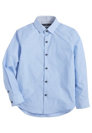 Chemise bleu clair à manches longues avec col pointu et boutons foncés, soigneusement étalée à plat sur un fond blanc.