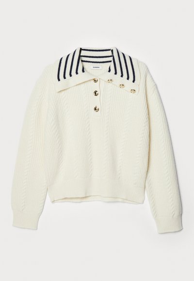 Hvid striktrøje med ribbestruktur, der har en bred stribet krave i marineblå, tre guldknapper og en cropped længde.