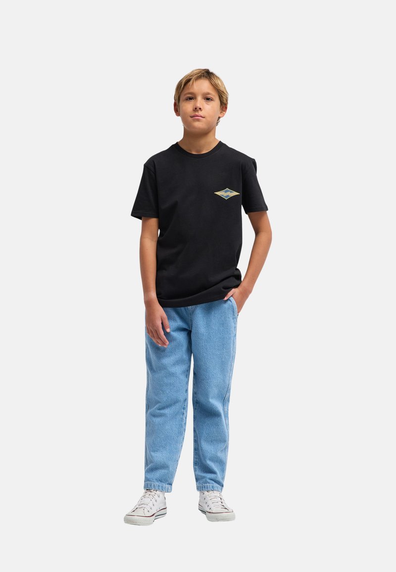 Czarny bawełniany t-shirt z małym niebiesko-żółtym logo w kształcie diamentu na klatce piersiowej, zestawiony z jasnoniebieskimi dżinsami i białymi trampkami.