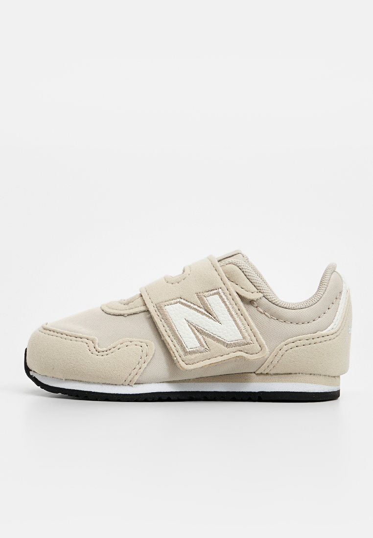 Sneaker beige con strap in velcro, materiale scamosciato morbido, punta arrotondata, cuciture a contrasto e logo "N" bianco di lato. Suola nera.