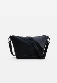 Bolso cruzado de cuero negro con un diseño triangular, acentos de malla, costuras en contraste y una correa ajustable.