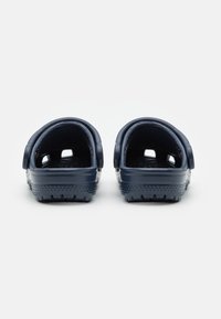 Navy blue slip-on clogs made from glossy plastic with ventilation holes and textured soles, featuring curved backs and raised side edges.
