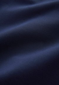 Tissu bleu marine avec une texture lisse et mate, présentant des ondulations et des plis subtils, indiquant un matériau léger.