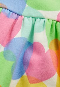 Multicolore stof met grote hartpatronen in roze, blauw, groen en geel, met een zachte textuur en geplooide naaddetails.