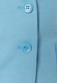 Light blue knit fabric with a textured pattern. Features a round plastic button with four holes, attached to a garment.