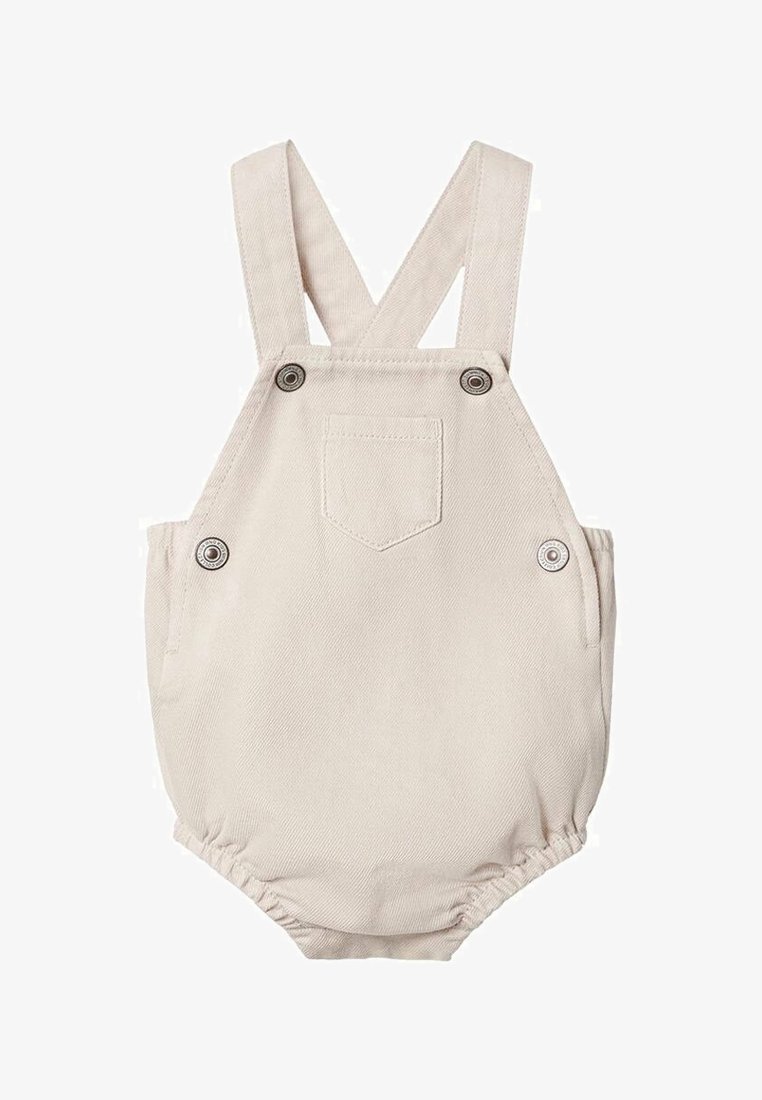 Beige bomullsromper med justerbara axelremmar, knappfästen och en liten ficka fram. Har elastiska benöppningar.