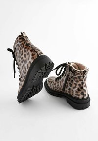 Botas de tobillo con estampado de leopardo y acabado brillante, suela de goma negra, parte delantera con cordones y cierre de cremallera en el lateral. Interior forrado de forro polar.