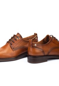 Chaussures en cuir marron à lacets avec une finition lisse, un bout arrondi, des coutures contrastées et des œillets en métal. Design à talon bas empilé.