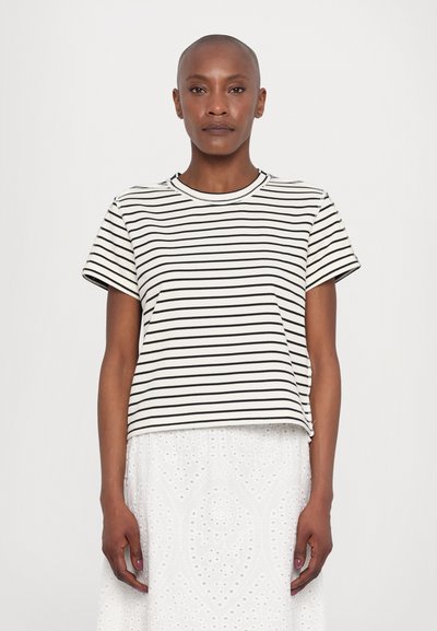Tricou pe rayuri alb și negru din bumbac; mâneci scurte, decolteu rotund, croială lejeră. Purtați cu o fustă albă texturată.