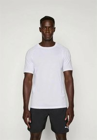 Hvid kortærmet træningsskjorte med rund hals, lavet af letvægtsstof, sammen med sorte shorts, der har et logo på shortsen.