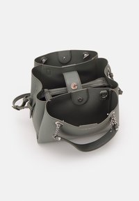 Kožená kabelka v tlumené zelené barvě s texturovaným povrchem, s utaženým vrškem, několika přihrádkami a akcenty ze stříbrného kovu.