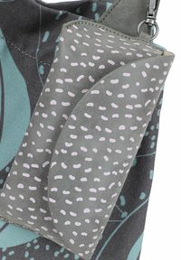 Borsa di stoffa grigia con motivi a pallini rosa chiaro, attaccata a una borsa più grande e decorata con elementi color teal e grigio scuro.