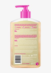 Clear pump bottle of gradual self tan gel with shimmer, showing detailed usage instructions, ingredients, and vegan certification on the label.