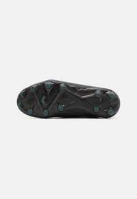 Black football boot sole with a textured surface, featuring eight teal studs and a distinctive zigzag pattern for traction.