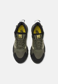 Chaussures de sport vertes et noires avec une tige en mesh, un embout renforcé, un col rembourré et un logo jaune. Présentent des motifs texturés et une semelle durable.