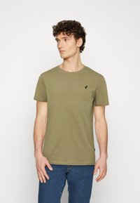 Olive green cotton t-shirt with a round neckline, short sleeves, and a small black logo detail on the left chest. Classic fit.