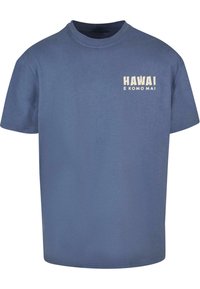 Blå bomull T-skjorte med korte ermer, med hvit tekst "HAWAI E KOMO MAI" på venstre brystområde. Klassisk rund hals-design.