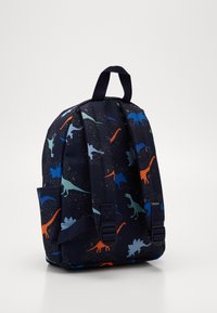 Mochila azul marino con correas ajustables que presenta siluetas de dinosaurios en colores naranja, azul y azul claro.