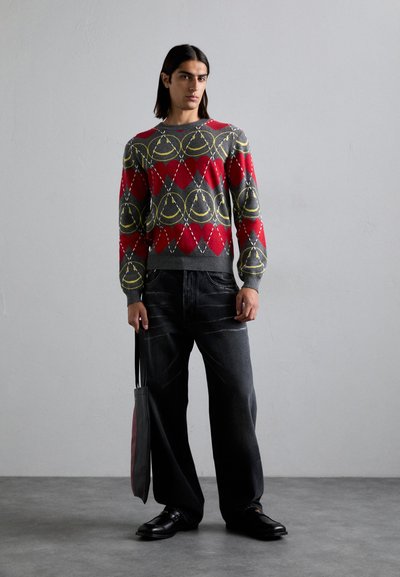 Rood en grijs gebreid sweater met diamantpatronen, gecombineerd met donkere wijde jeans en zwarte schoenen, met een grijs en rood tote bag.