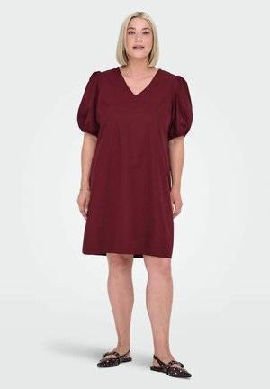 Burgundy short dress with a V-neck and puffed sleeves, made of smooth fabric. Worn with black flats featuring silver studs.