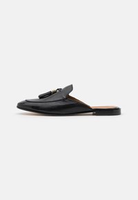 Sorte skinn slip-on sko med spiss tå og flat hæl. Har dekorativ dusk og minimal sømdetaljer.