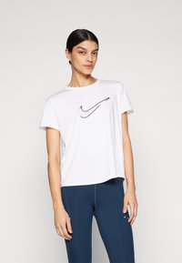Hvit T-skjorte med korte ermer fra Nike med svart swoosh-logo på brystet, kombinert med mørkeblå tights med subtile sømdetaljer.