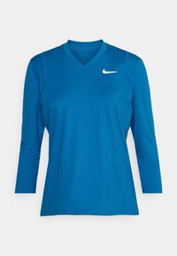 Niebieska, długosleeve sportowa koszulka z dekoltem w serek i białym logo Nike swoosh na prawej piersi.