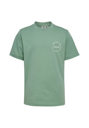 Grünes T-Shirt mit kurzen Ärmeln und Rundhalsausschnitt mit kleinem weißem rundem Logo und Text auf der linken Brust mit der Aufschrift „hummel serving the game since 1923.“