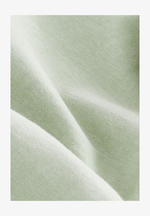 Ljust grönt bomullstyg med en jämn textur, som visar fina, jämna vävar och en subtil lyster. Materialet har en mjuk, följsam kvalitet.