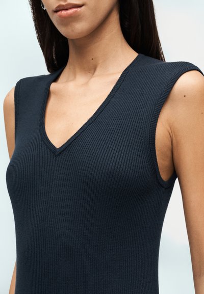Μπλε ναυτικό ριμπ αμάνικο τοπ με βαθύ V-λαιμόκοψη και εφαρμοστή γραμμή, που αναδεικνύει την υφή και τις ομαλές καμπύλες του υφάσματος.