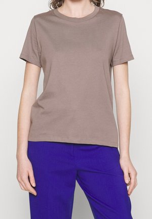 Brown cotton t-shirt with a crew neck, short sleeves, and a subtle Calvin Klein logo. Paired with blue trousers, featuring a smooth texture.